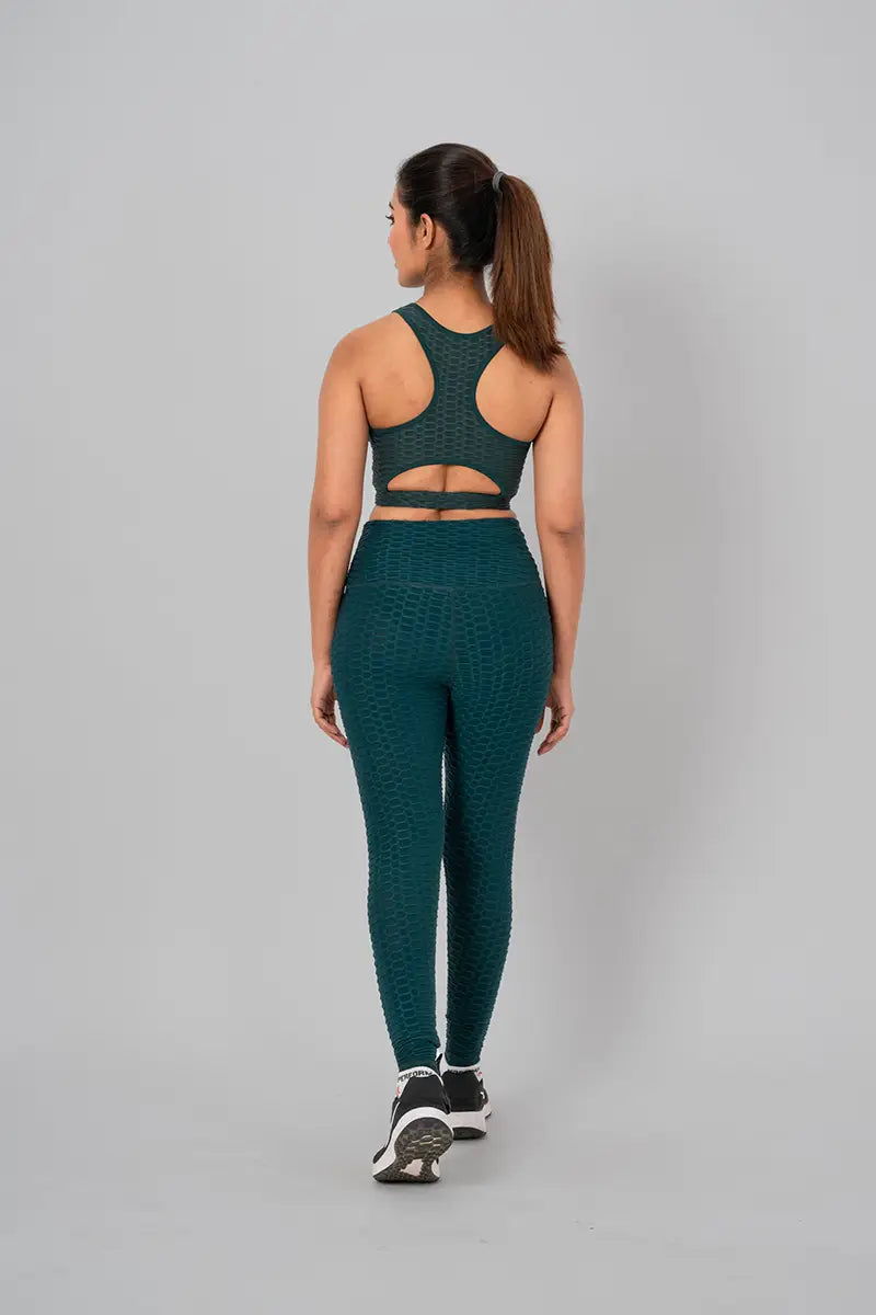 Woman in womens gym wear, bottle green coord set - back view standing, highlighting open back keyhole design and medium support.