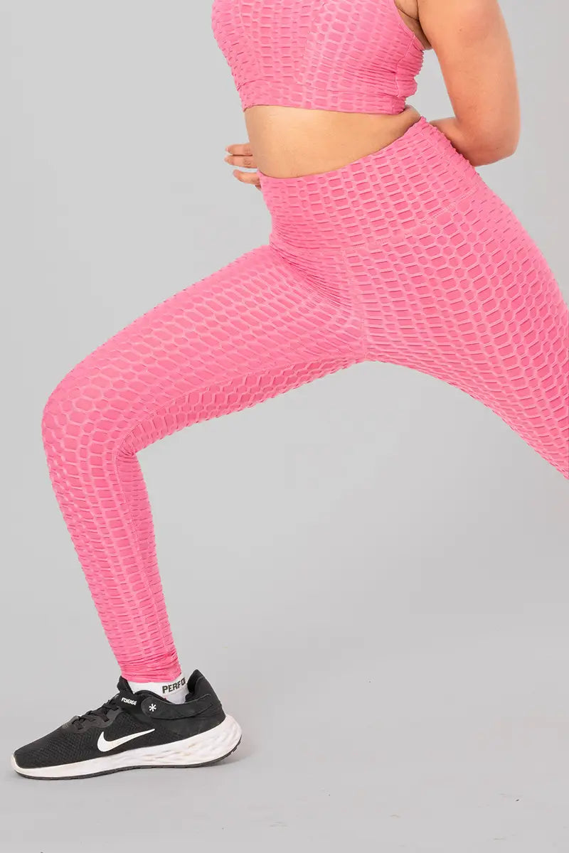 Woman in activewear, pink leggings - leg stretch pose demonstrating flexibility and breathable fabric.