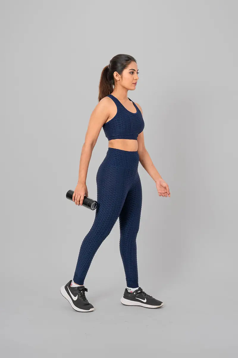 Woman in activewear set, navy blue coord - walking front view with bottle, featuring stretchable and breathable material.