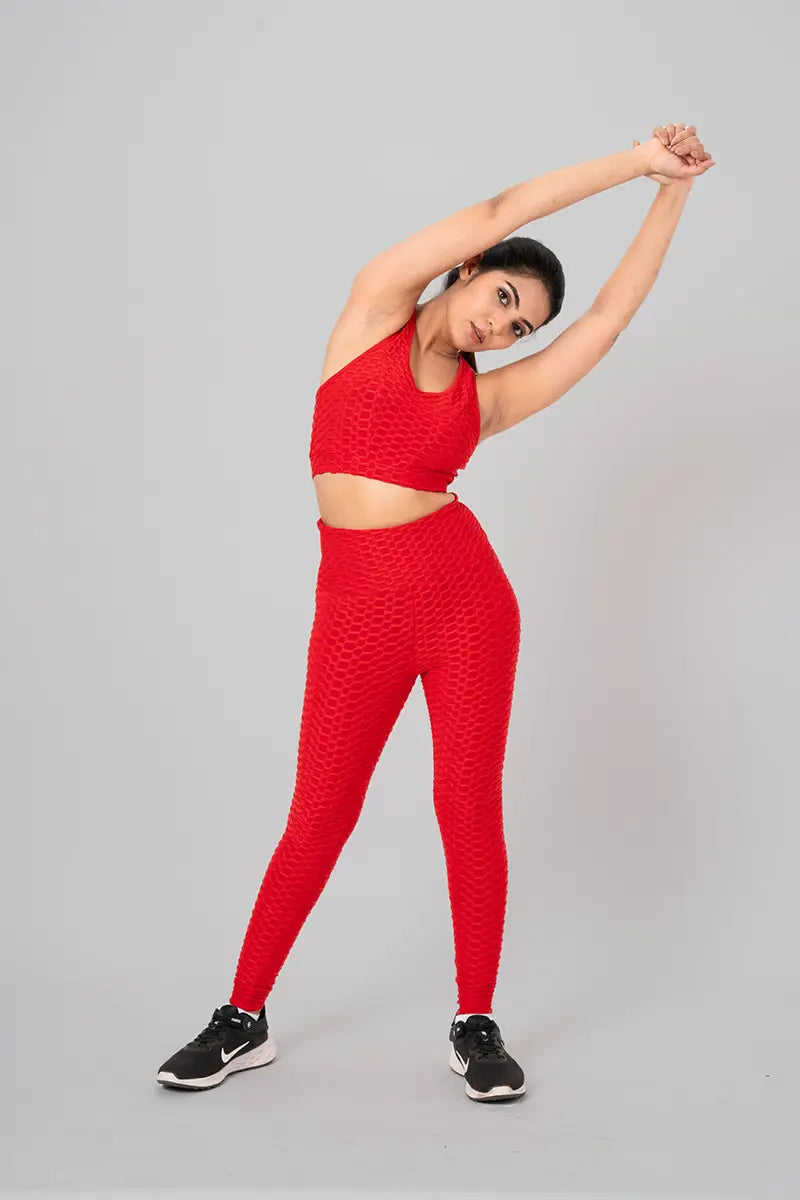 Woman in gym clothes coord set, red - side stretch pose demonstrating flexibility and moisture-wicking properties.