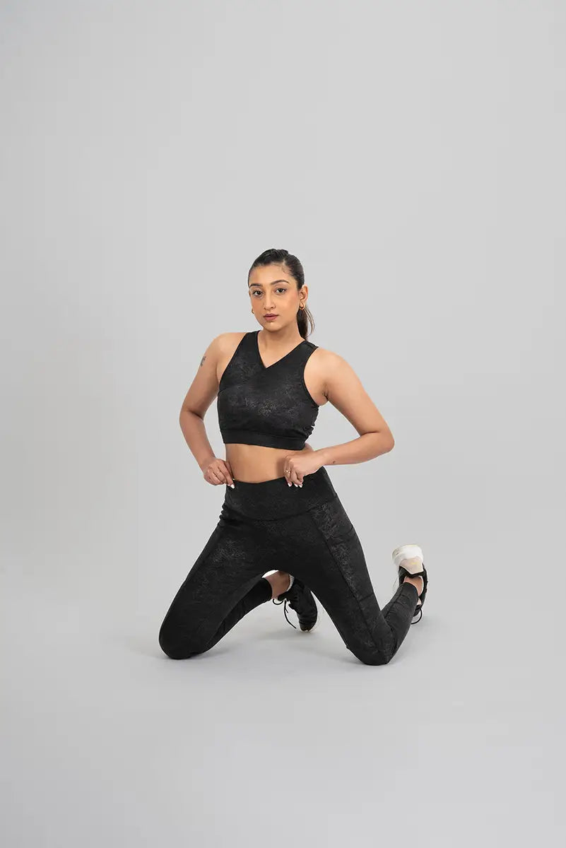 Woman in gym leggings, black metallic - kneeling pose demonstrating flexibility and squat-proof material.