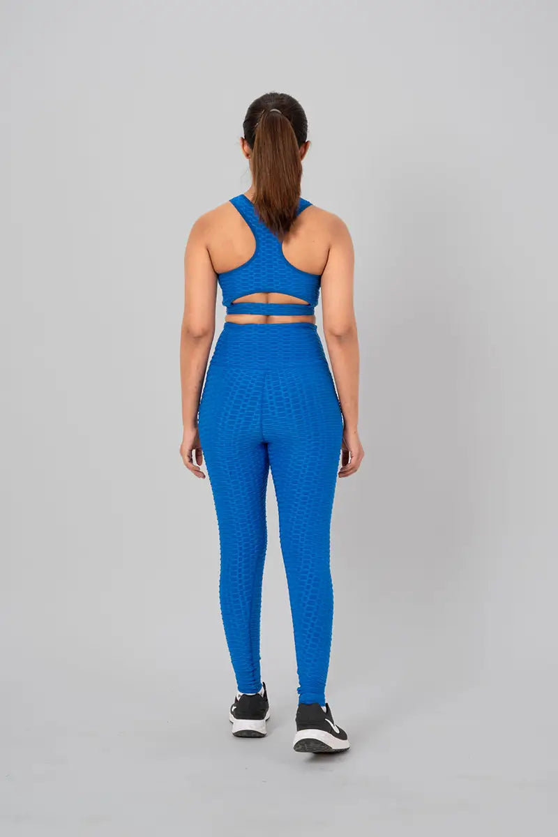 Woman in gym outfits, teal blue coord set - back view standing showing open back keyhole design and medium support.