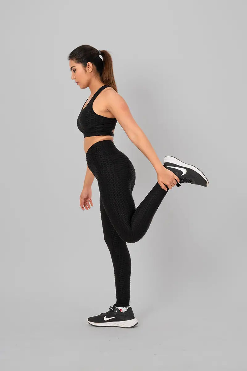 Women in gym wear, coord set - stretching with leg up, demonstrating stretchable, breathable, and moisture-wicking fabric.