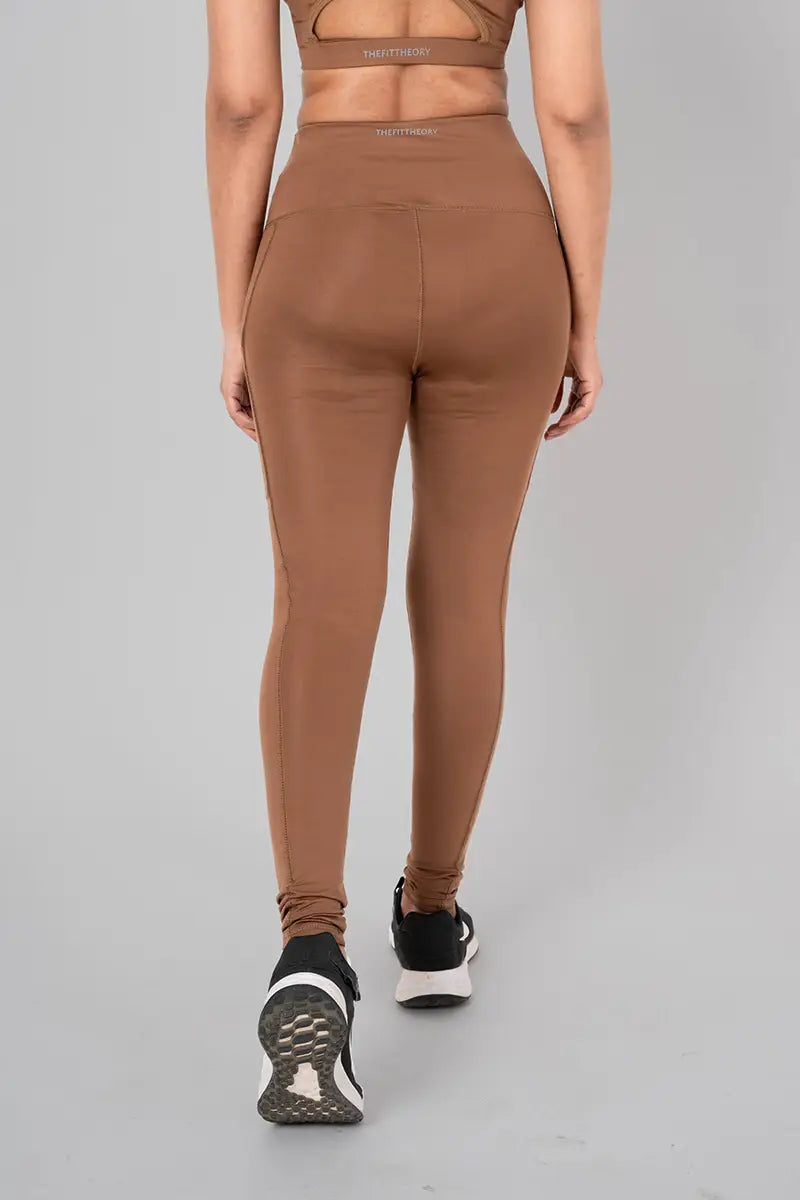 Woman in leggings with pockets, front view showing high-waisted fit and breathable, sweat-wicking fabric. @@@color_cocoa