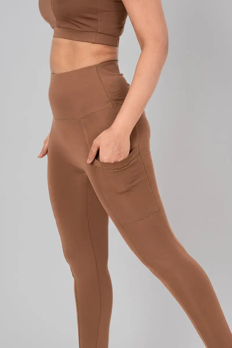 Woman in leggings with pockets, front view showing high-waisted fit and breathable, sweat-wicking fabric. @@@color_cocoa