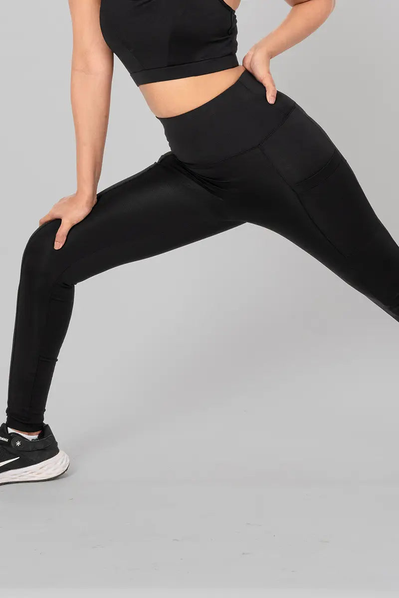 Woman in high waisted black leggings - side lunge pose demonstrating flexibility and stretchable material.