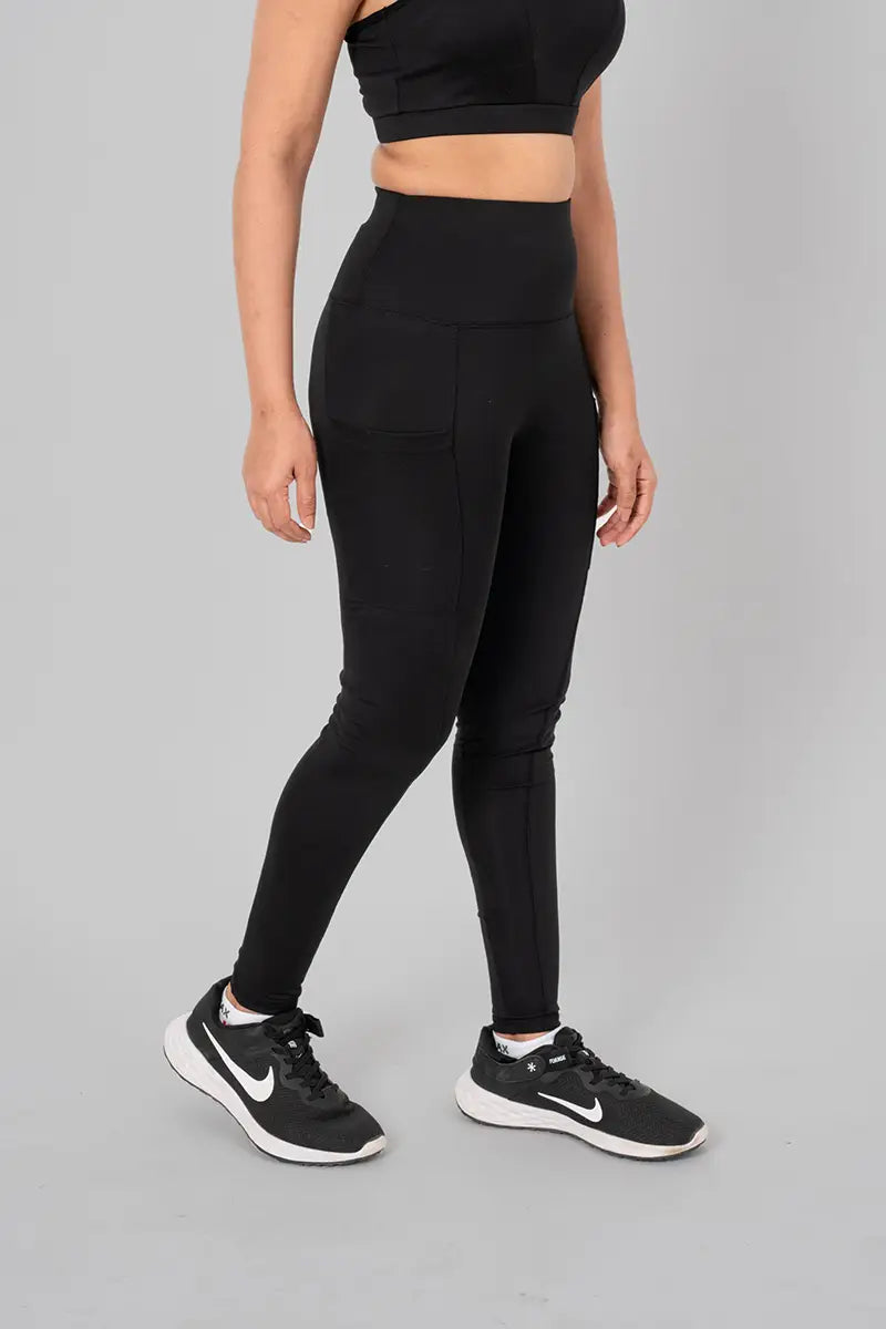 Woman in high waisted black leggings - side standing pose highlighting squat-proof material and breathable fabric.