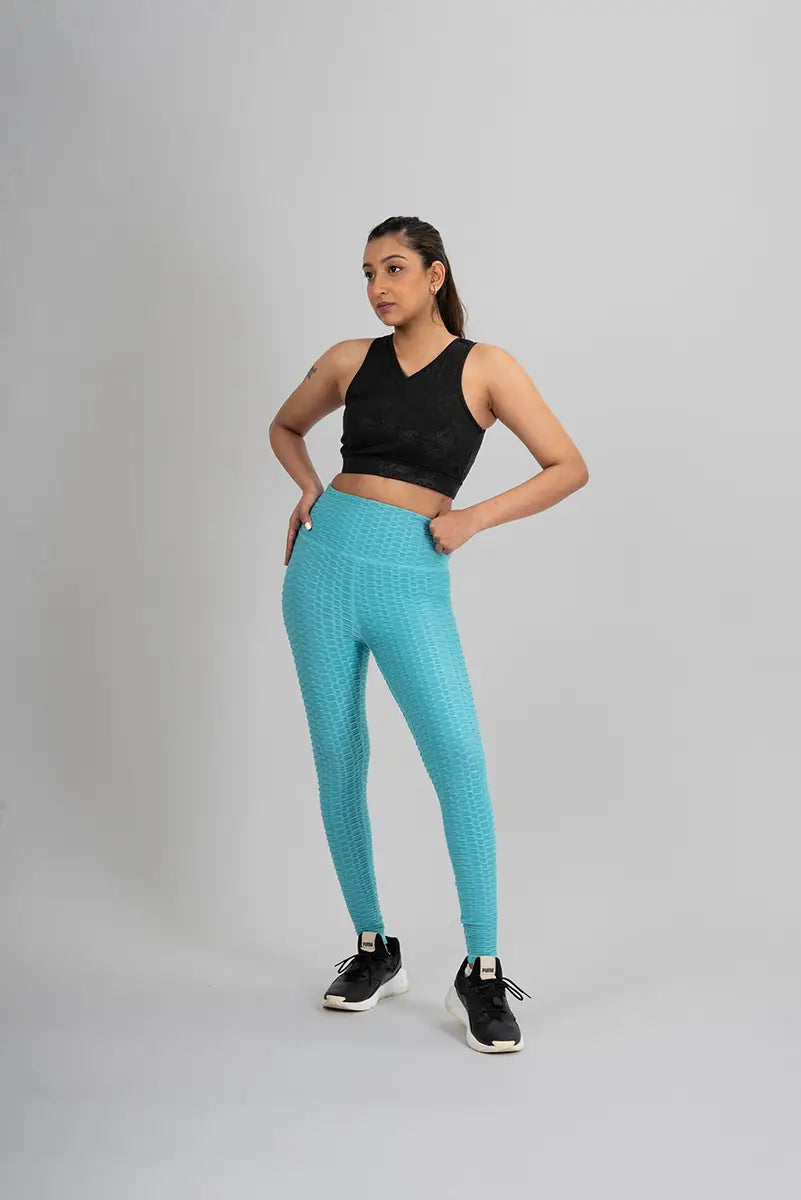 Woman in high waisted leggings, aqua blue - front view with hands on waist, demonstrating anti-cellulite fabric and medium compression.