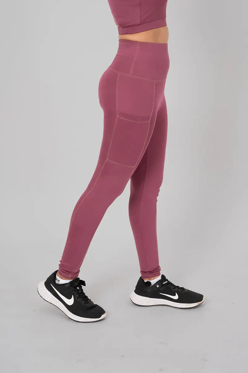 Woman in tights for womens workout, black - side standing pose showing functional pocket and high-waisted fit.