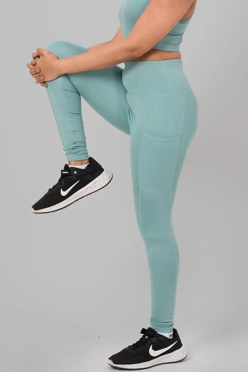 Woman in activewear pants, mist - high knee stretch pose demonstrating flexibility and breathable fabric.