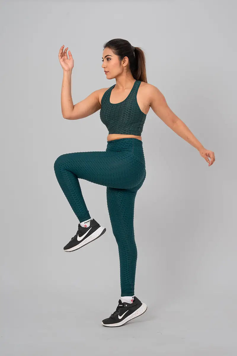 Woman in womens gym wear, bottle green coord set - performing high knee exercise, demonstrating breathable, stretchable fabric.