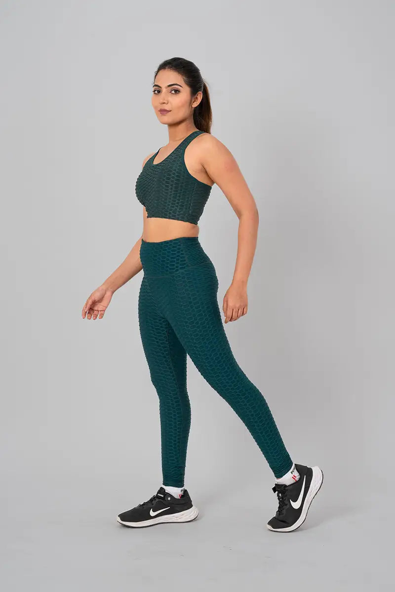 Woman in womens gym wear, bottle green coord set - walking side view, highlighting 4-way compression and flexibility.