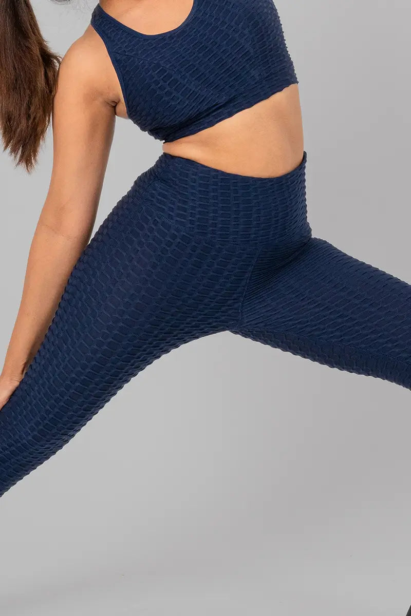 Woman in workout clothes, navy blue leggings - leg stretch pose demonstrating medium compression and breathable fabric.