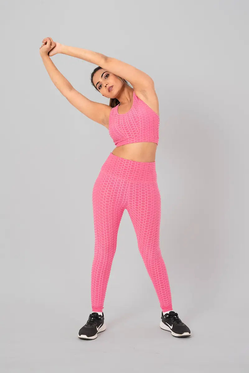 Woman in workout clothes, pink coord set - side stretch pose emphasizing flexibility and breathable fabric.