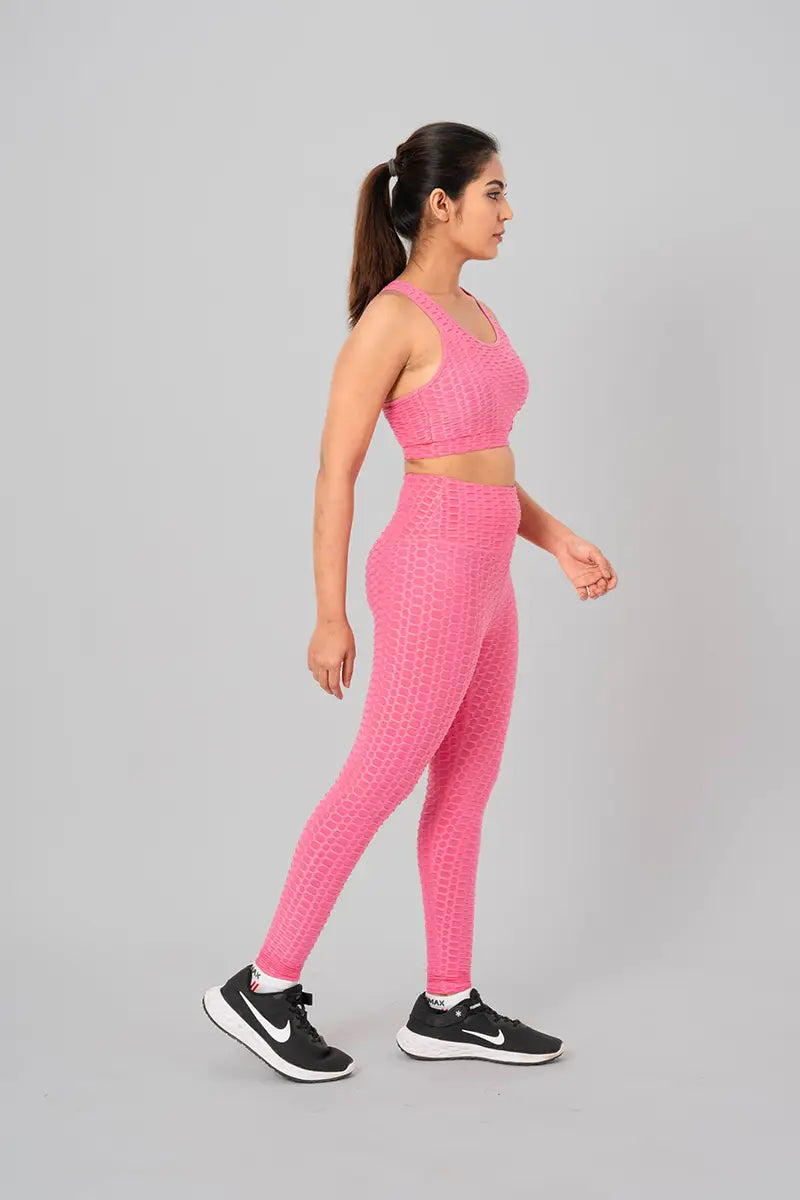 Woman in workout clothes, pink coord set - walking side view highlighting stretchable, moisture-wicking fabric.